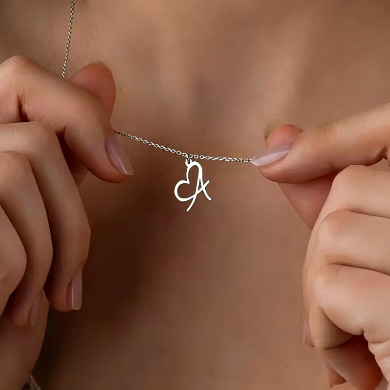 Heart Initial Necklace, silver-tone heart and letter pendant, held in the hand
