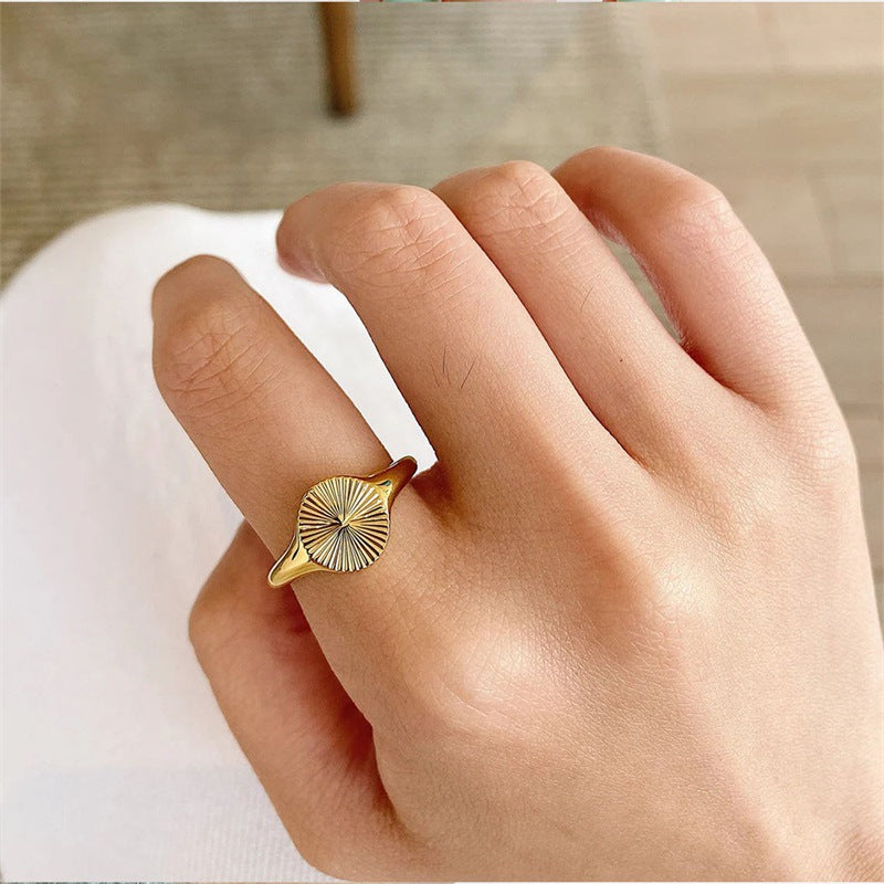 Mila Sunburst Ring, gold sunburst signet ring close-up on a finger