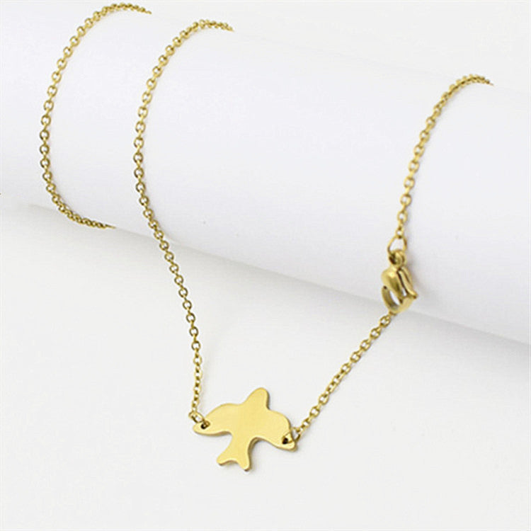 Little Dove Necklace, dainty gold dove pendant on a fine chain, flat on ivory